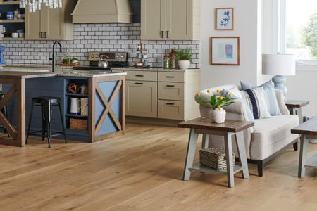 Warm wood flooring in an open-concept kitchen and living room with comfortable seating | Country Manor Decorating